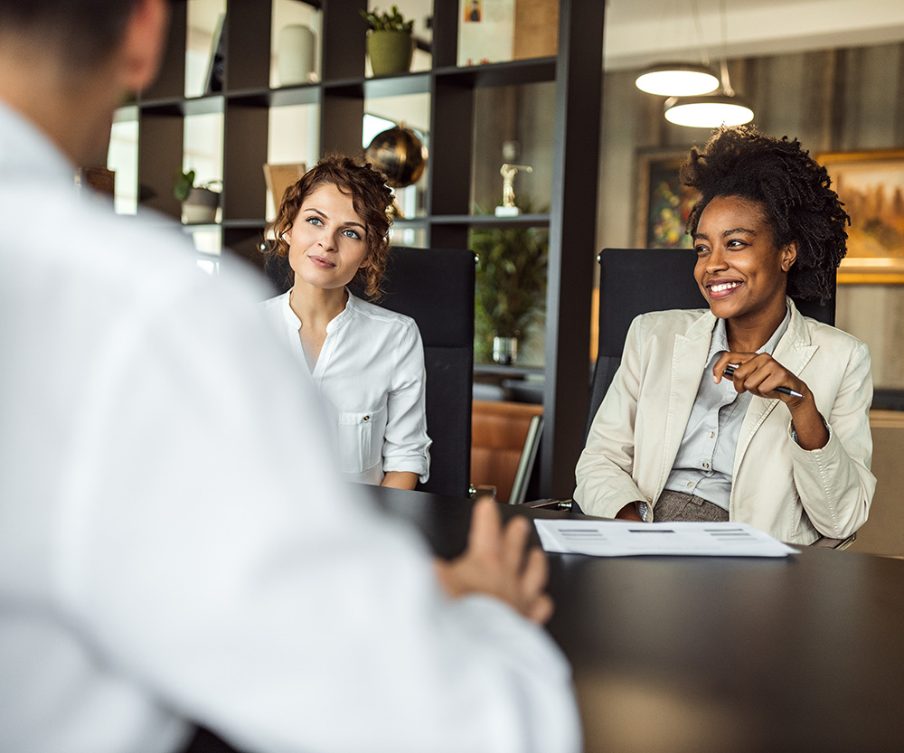 Person being interviewed by two women who are smiling